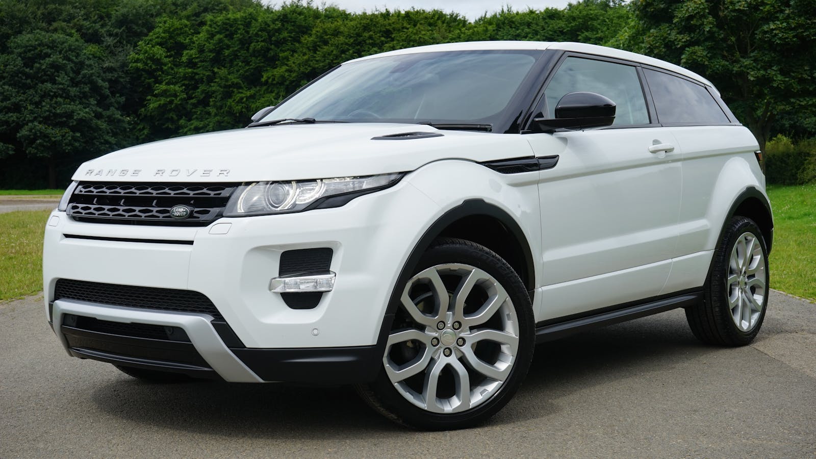 Commercial Auto, Auto, Stylish white Range Rover parked on a road in a green outdoor setting, showcasing its luxury design.